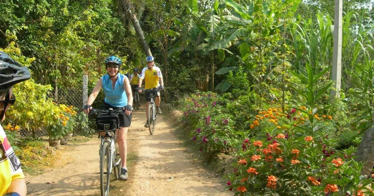 6 Amazing Cycling Trips Around The World 3 People cycling past flowers in the mekong delta